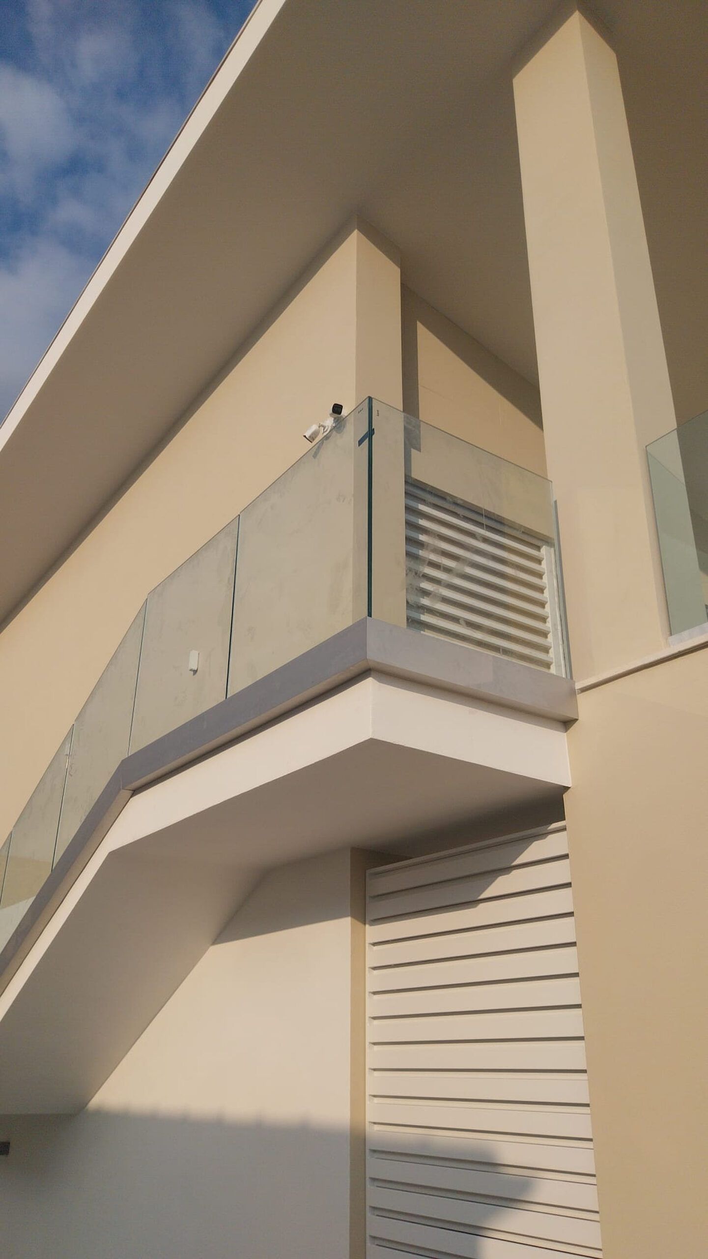 Esterno di un edificio moderno con balcone caratterizzato da ringhiere in vetro e metallo, pareti beige e dettagli bianchi MZ Sistemi Latina