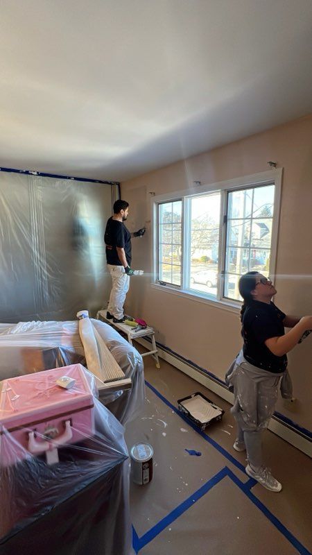 A man and a woman are painting a wall in a room.