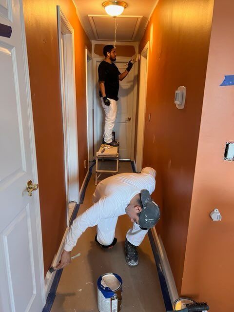 Two men are painting a hallway in a house.