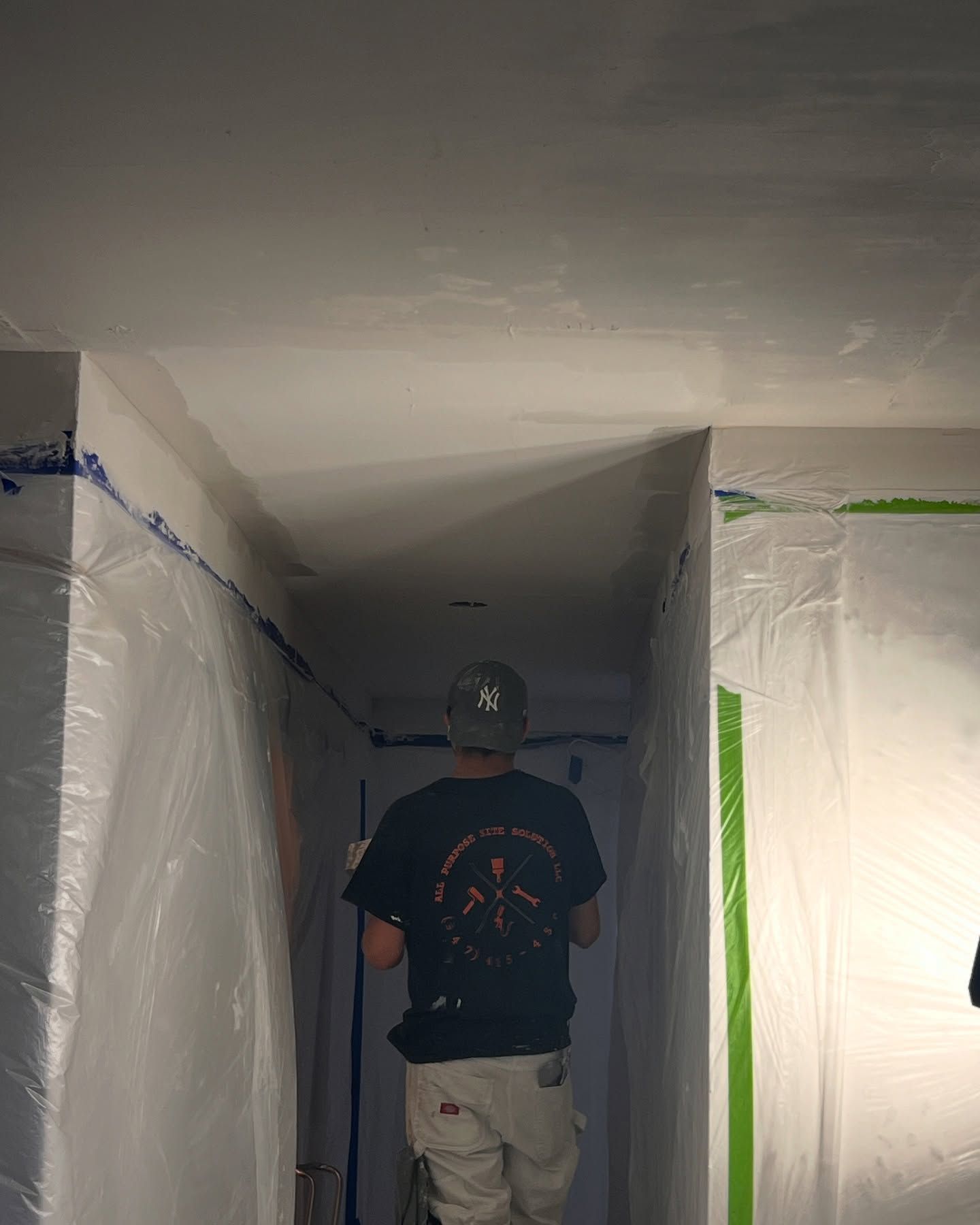 A man is standing in a hallway covered in plastic.