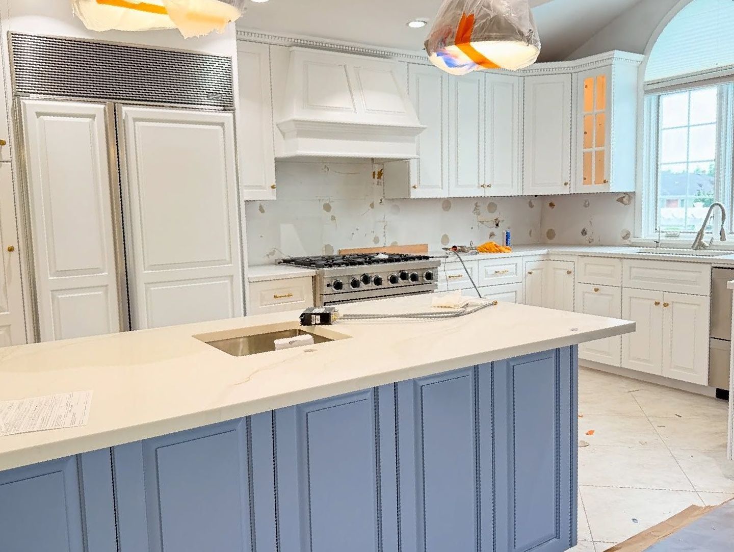 A kitchen with white cabinets and a blue island.
