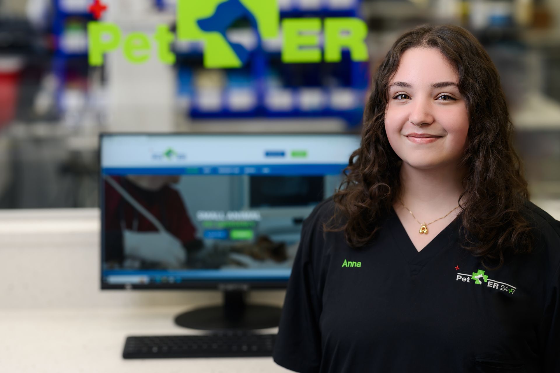 CT scan machine with a patient table, monitors, and medical equipment in a brightly lit room.