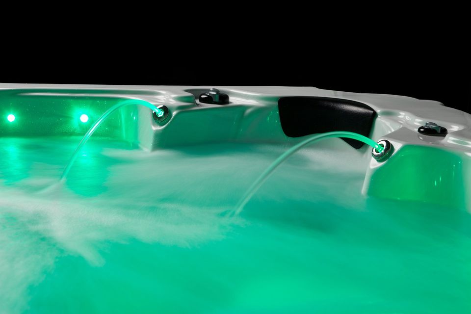 A hot tub with green lights on it is filled with water.