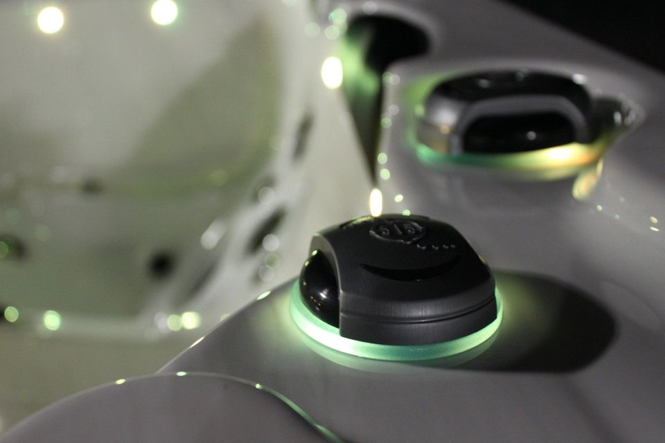 A close up of a hot tub with a green light on the side.