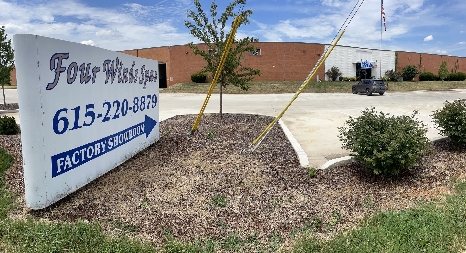 A large white sign in front of a factory with a phone number on it.