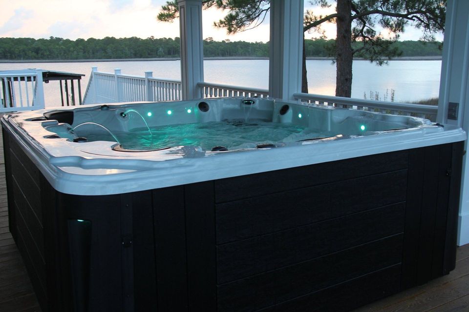 A large hot tub on a deck overlooking a lake