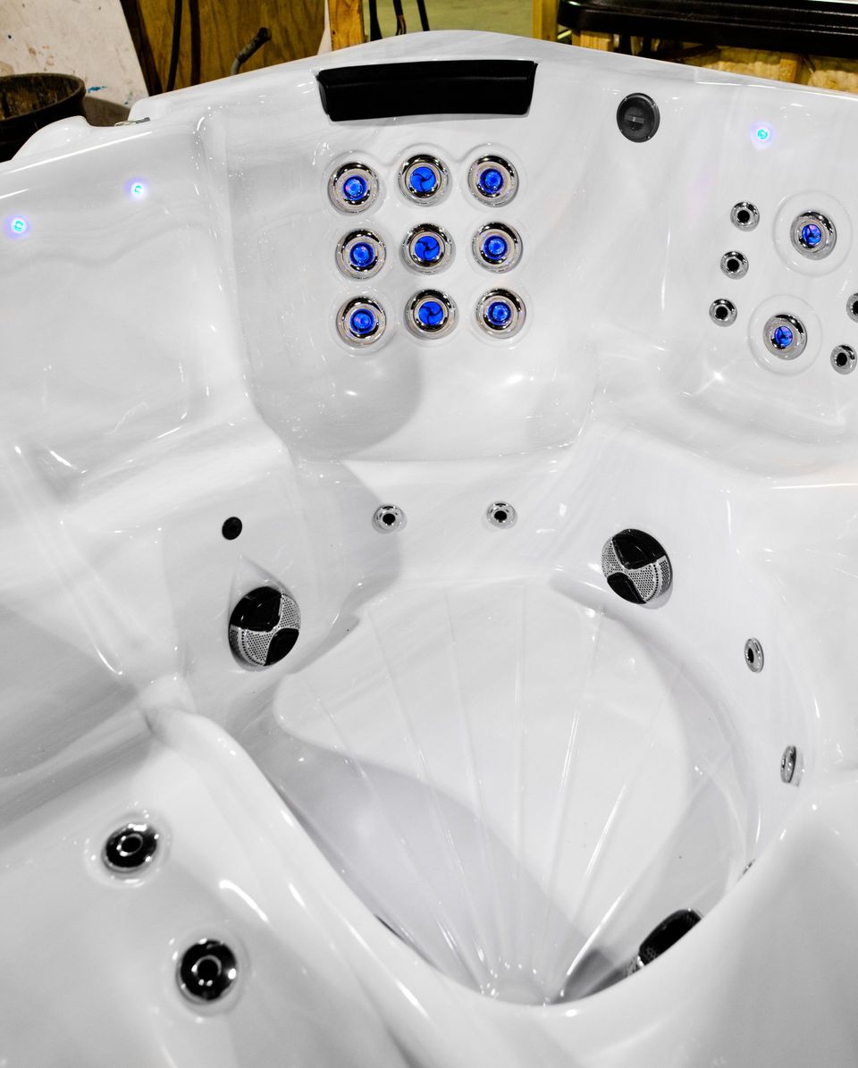 A white hot tub with blue jets is sitting on a wooden table.