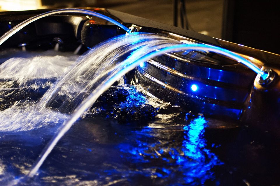 A waterfall in a hot tub with blue lights on it.