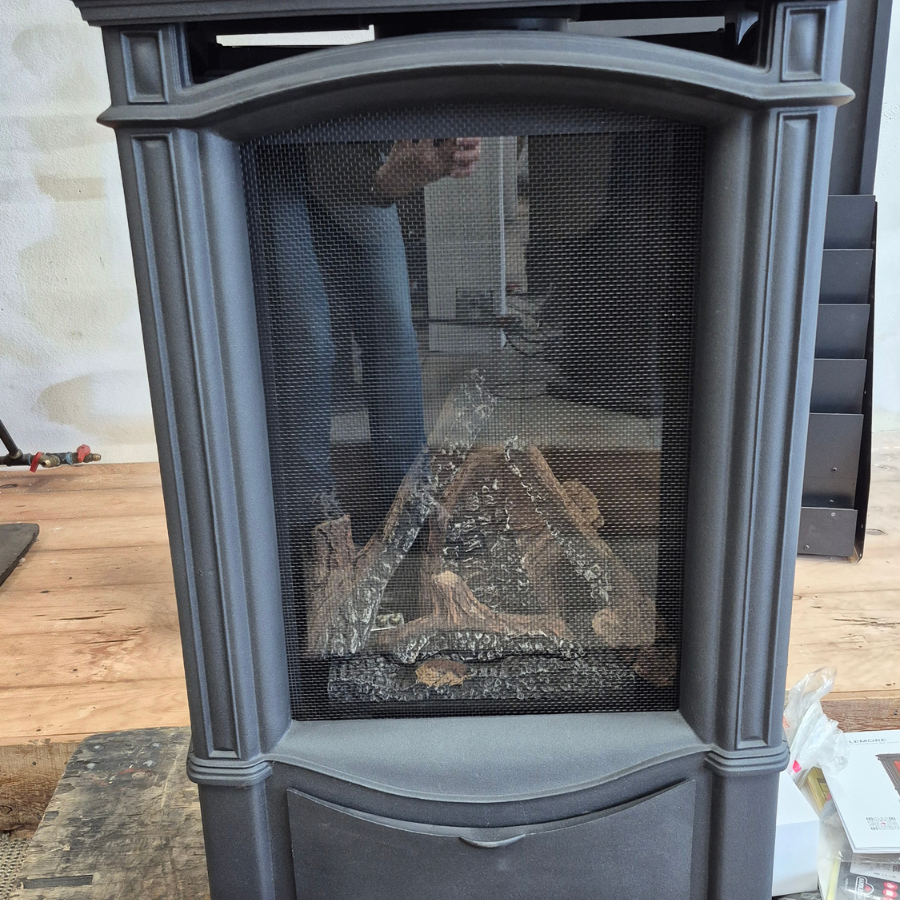 Napoleon Castlemore direct vent gas stove display model with black cast-style body, freestanding design, and realistic log set in Olympia WA