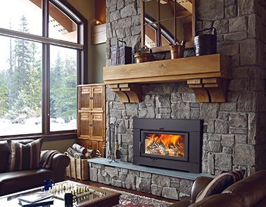 Fireplace in a cozy living room with a stone surround, wooden mantel, and a window overlooking a snowy landscape.