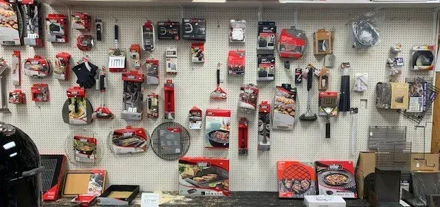 Display of various grilling tools and accessories on a pegboard at a store, with red and black packaging.