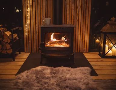 Indoor wood-burning stove with candles and decorative rug in cozy living room in Raymond, WA