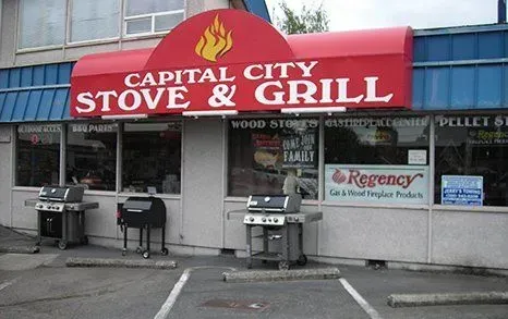 Capital City Stove & Grill store with red awning and various grills displayed outside.