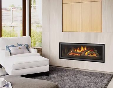 A modern living room with a gas fireplace, white chaise lounge, and wooden storage cabinet. The fireplace has a black frame.