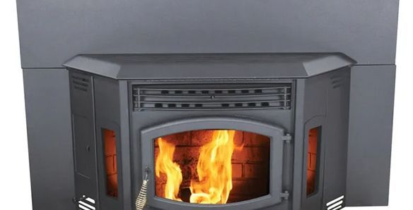 Close-up of a burning pellet stove with flames visible through the glass door; the stove is dark gray.