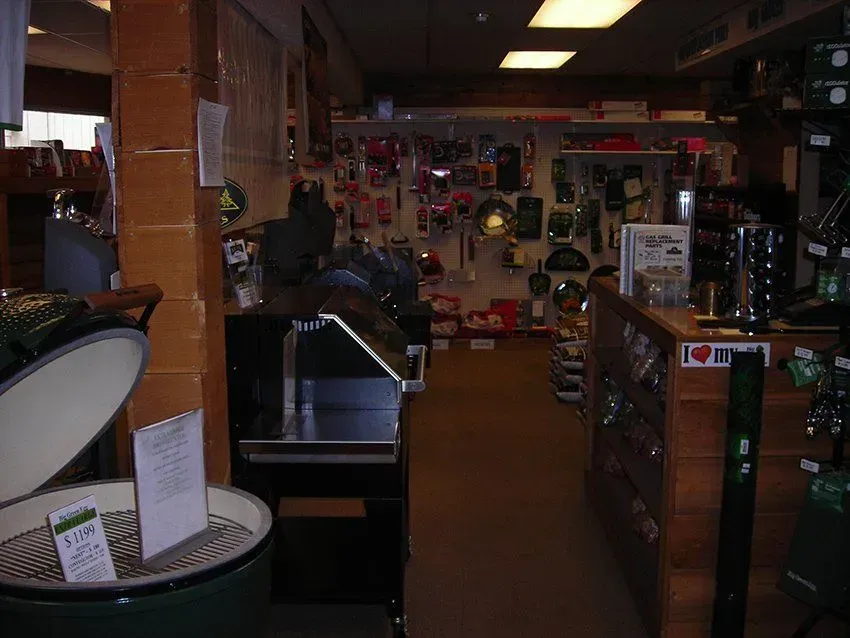 Interior of a store with grilling supplies. Various grilling tools and Big Green Egg grills are on display.