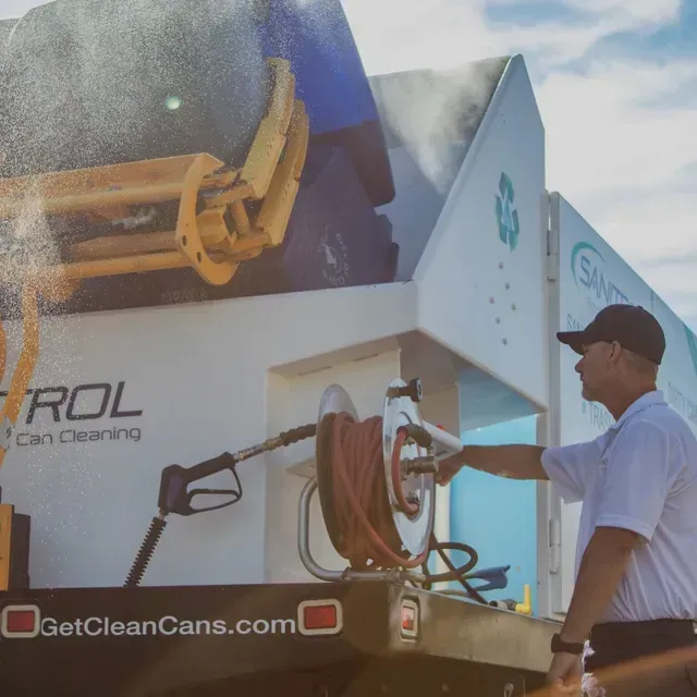 A man is standing in front of a truck that says getcleancans.com