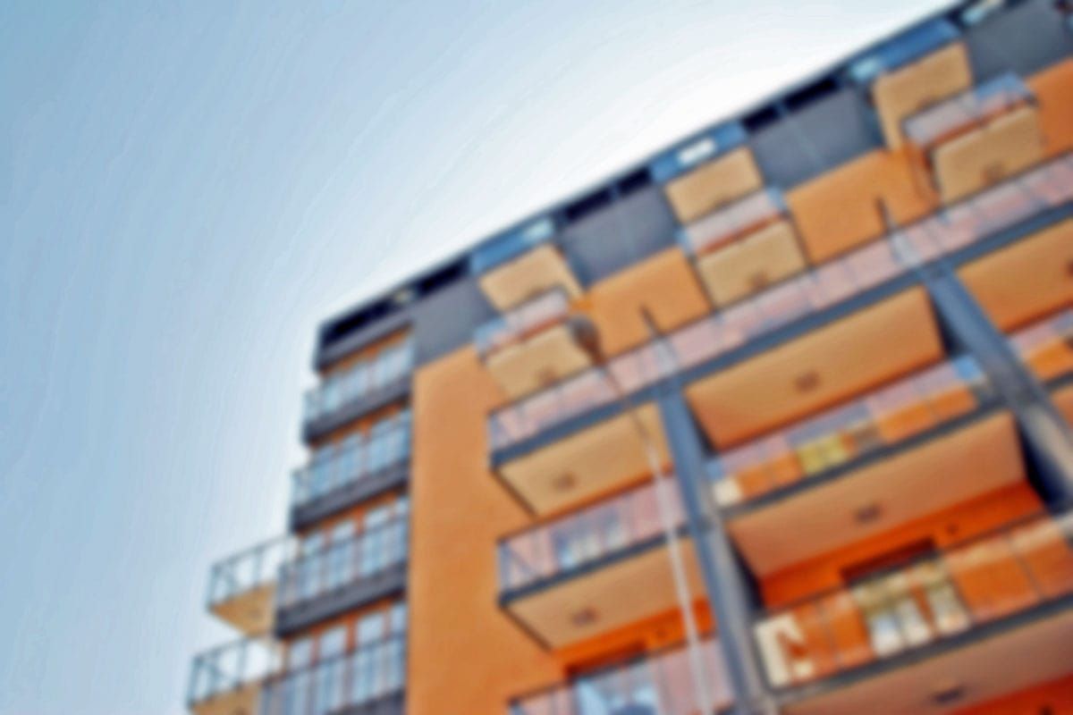 A blurry picture of a large apartment building with balconies against a blue sky.