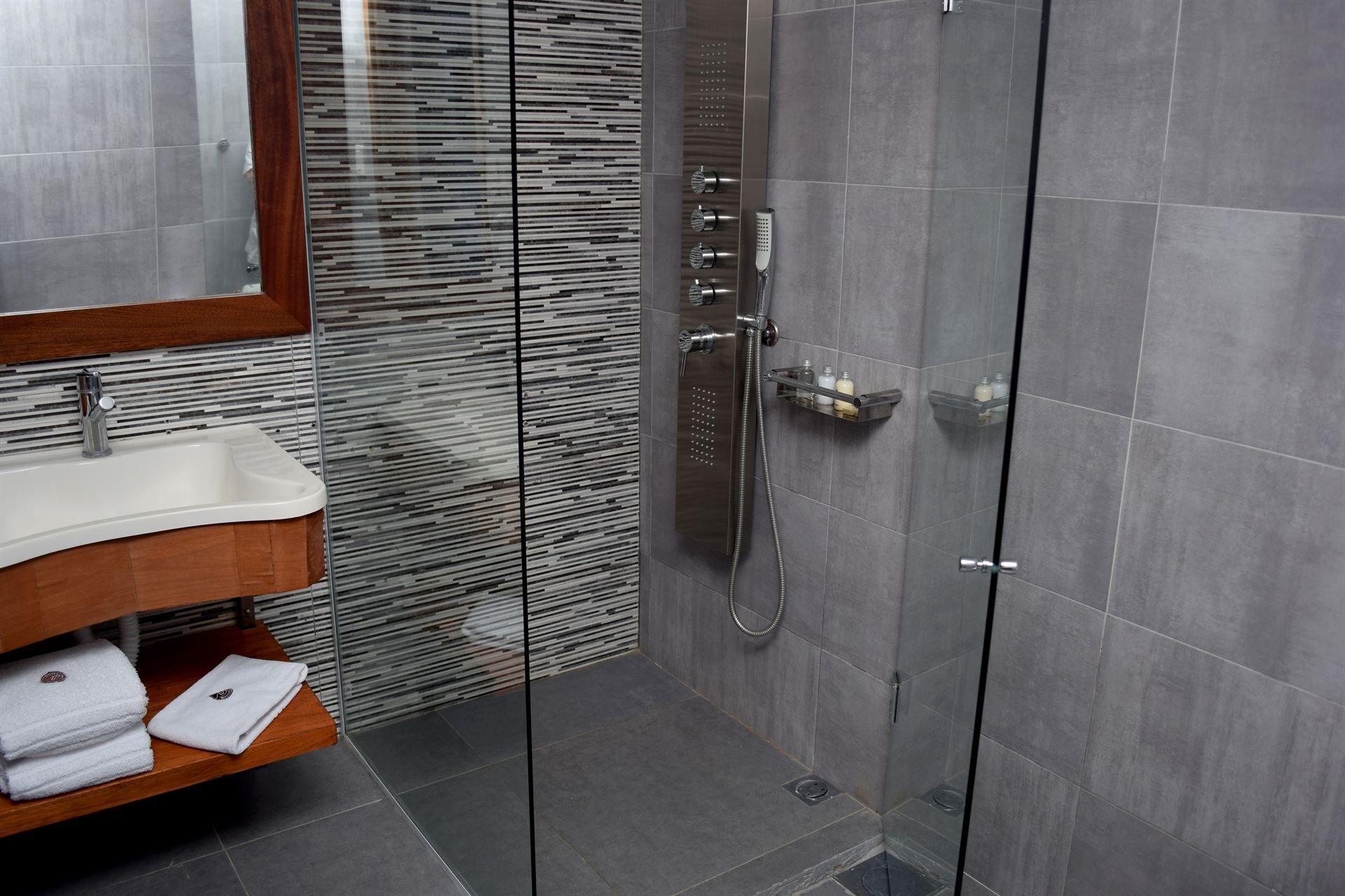 Un baño con ducha, lavabo y espejo.