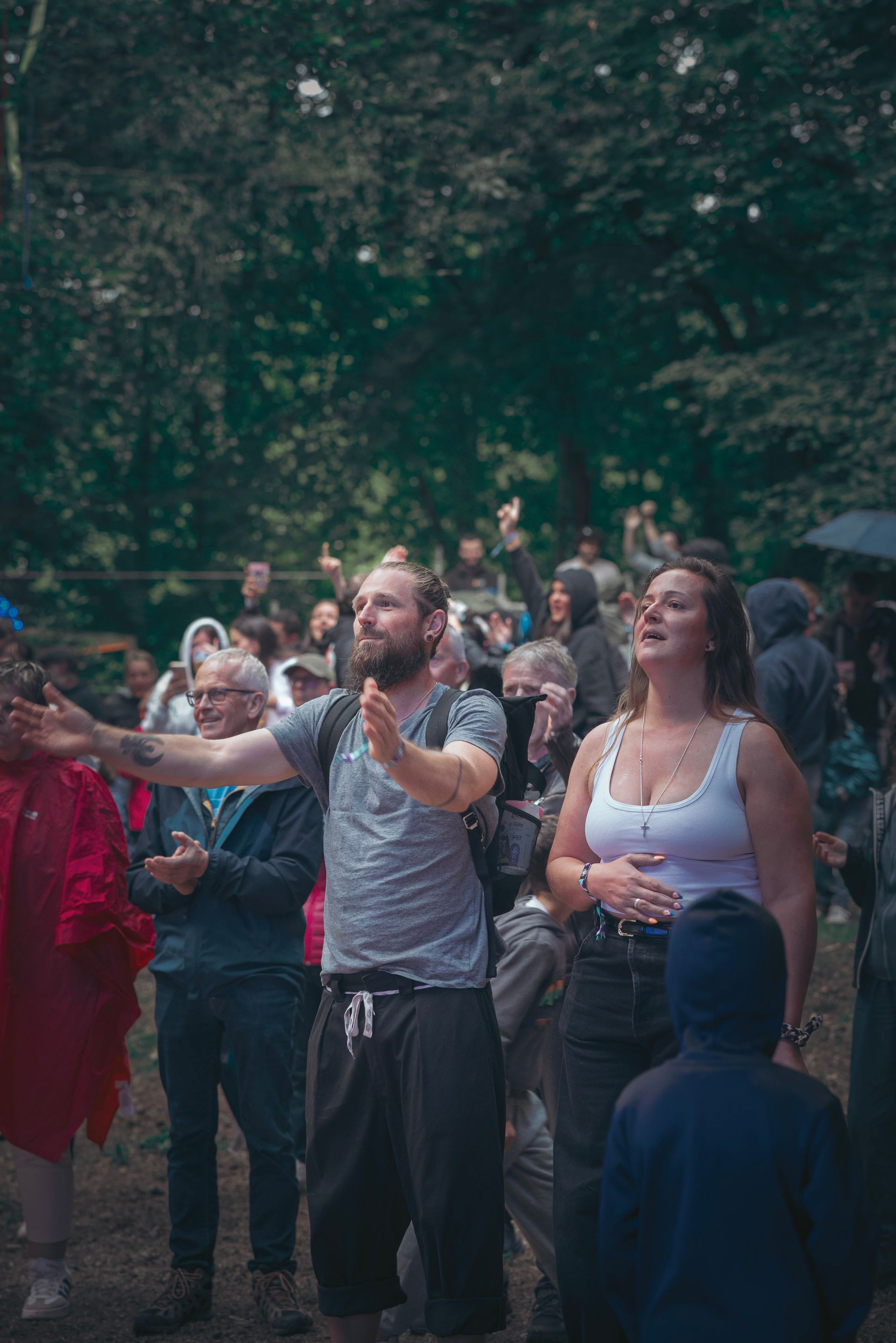 Une foule de personnes se tient à l'extérieur, certaines les bras tendus et levant les yeux au ciel avec enthousiasme.