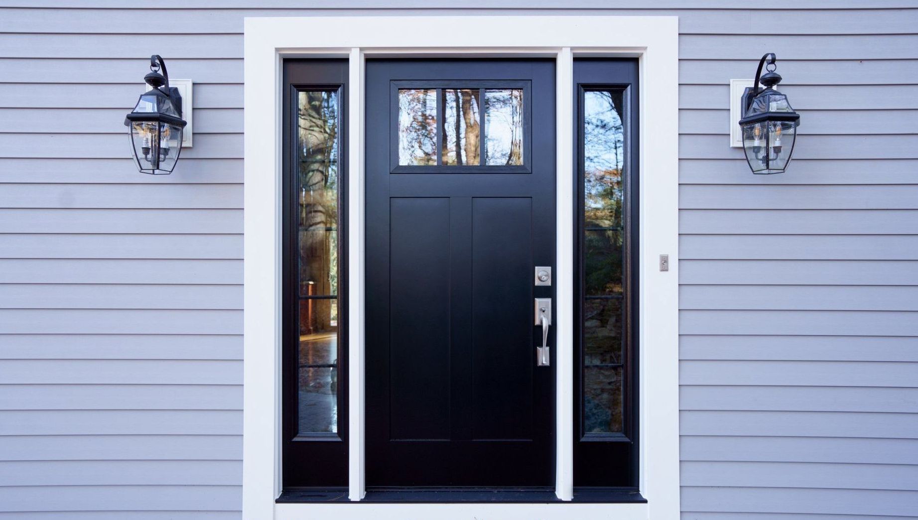 A black door with a white trim is on the side of a house.