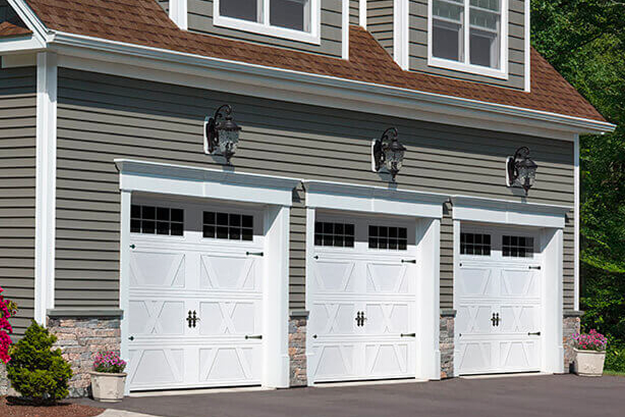 A house with three white garage doors and a brown roof.