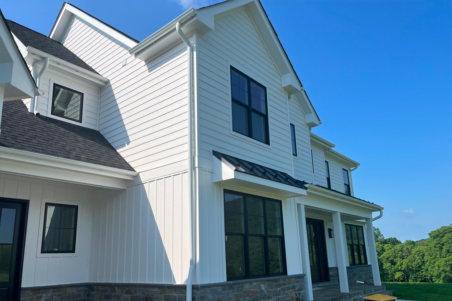 A large white house with black windows and a blue sky in the background.