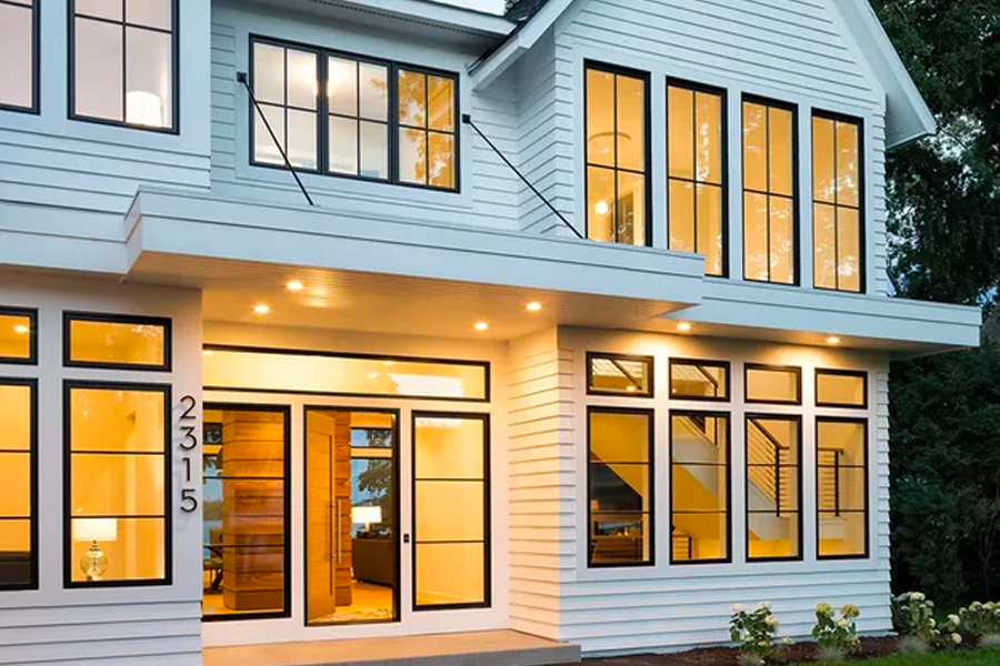 A large white house with lots of windows and doors is lit up at night.