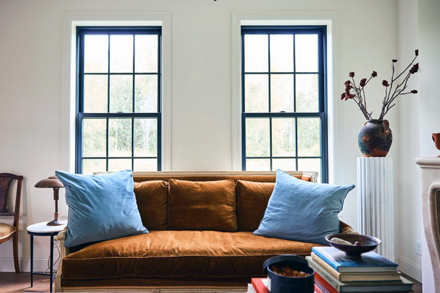 A living room with a brown couch and blue pillows.