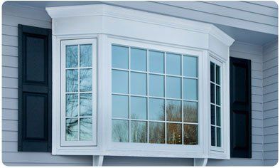 A white bay window with black shutters on a house