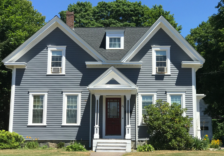 A gray house with white trim and a red door