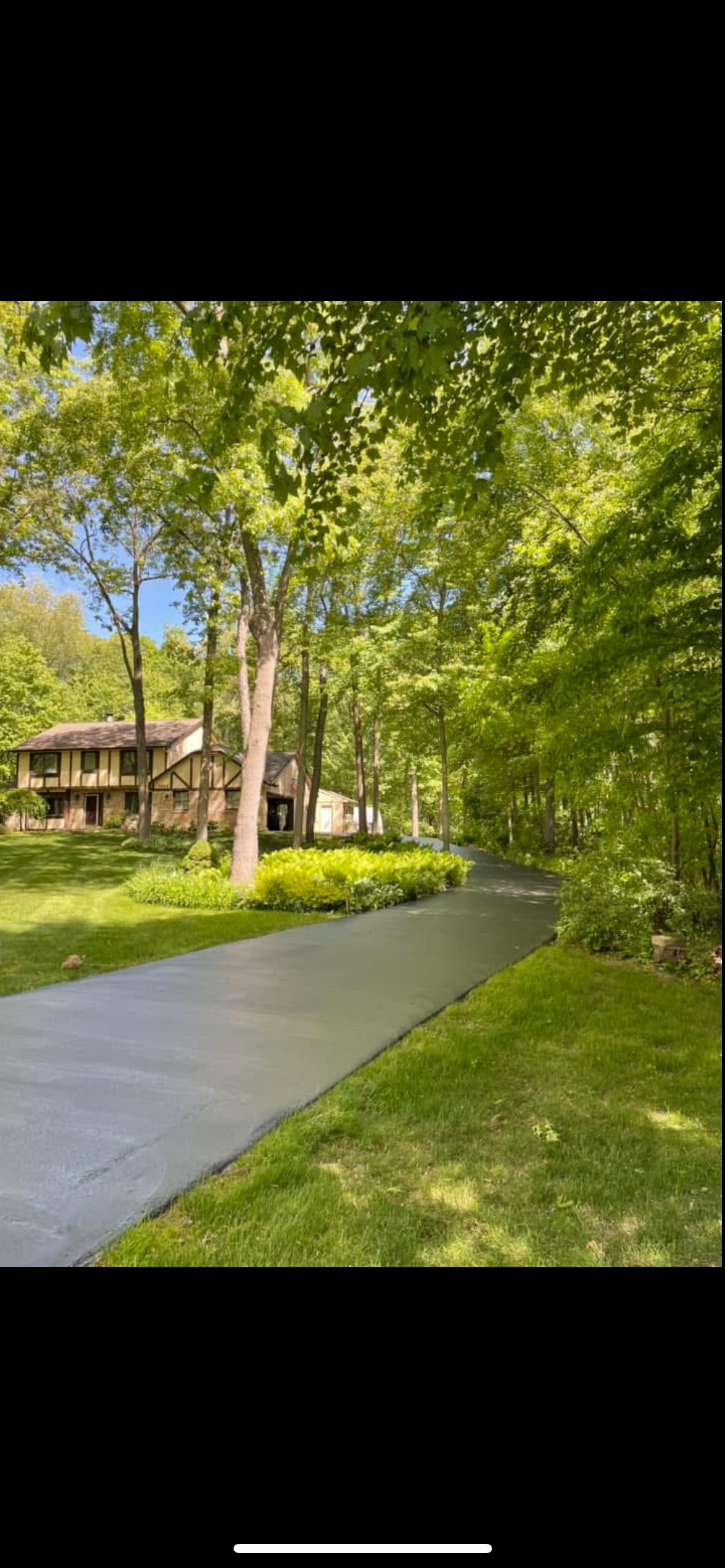 Tree-lined path beside a house in a sunny green yard