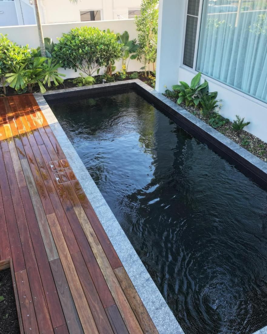 A lArge Swimming Pool Filled With Water Next to a Wooden Deck — Pools By Design in Buderim, QLD