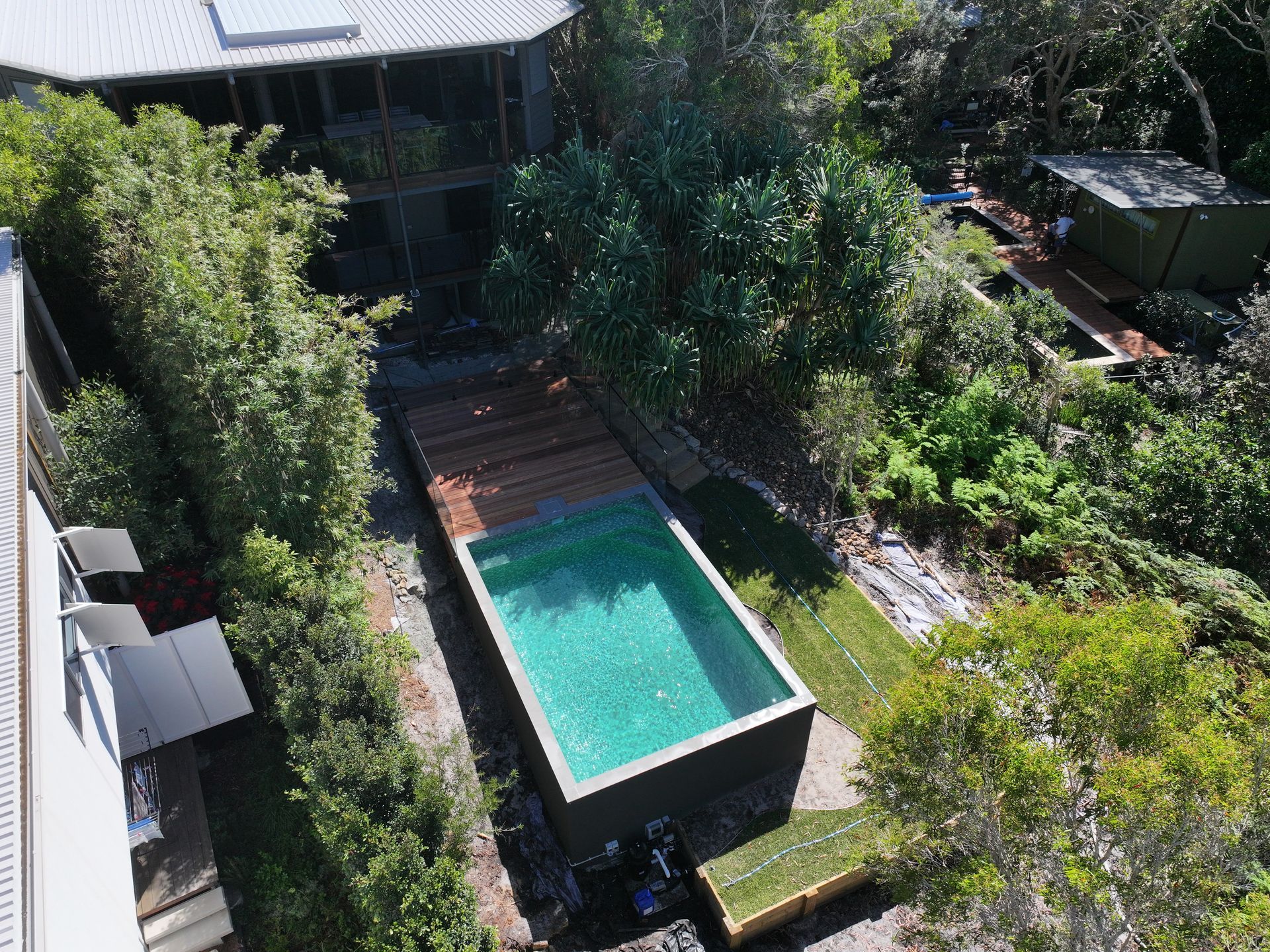 A Swimming Pool With Black Tiles and a Wooden Deck — Pools By Design in Aura, QLD