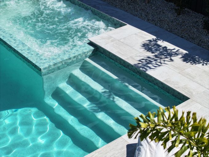 Swimming pool with turquoise water, built-in steps, and a jacuzzi, in a sunny setting — Pools By Design in Warana, QLD