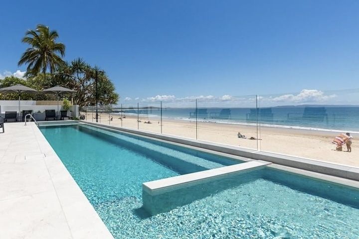 A Large Swimming Pool With a View of the Ocean and a Beach — Pools By Design in Warana, QLD