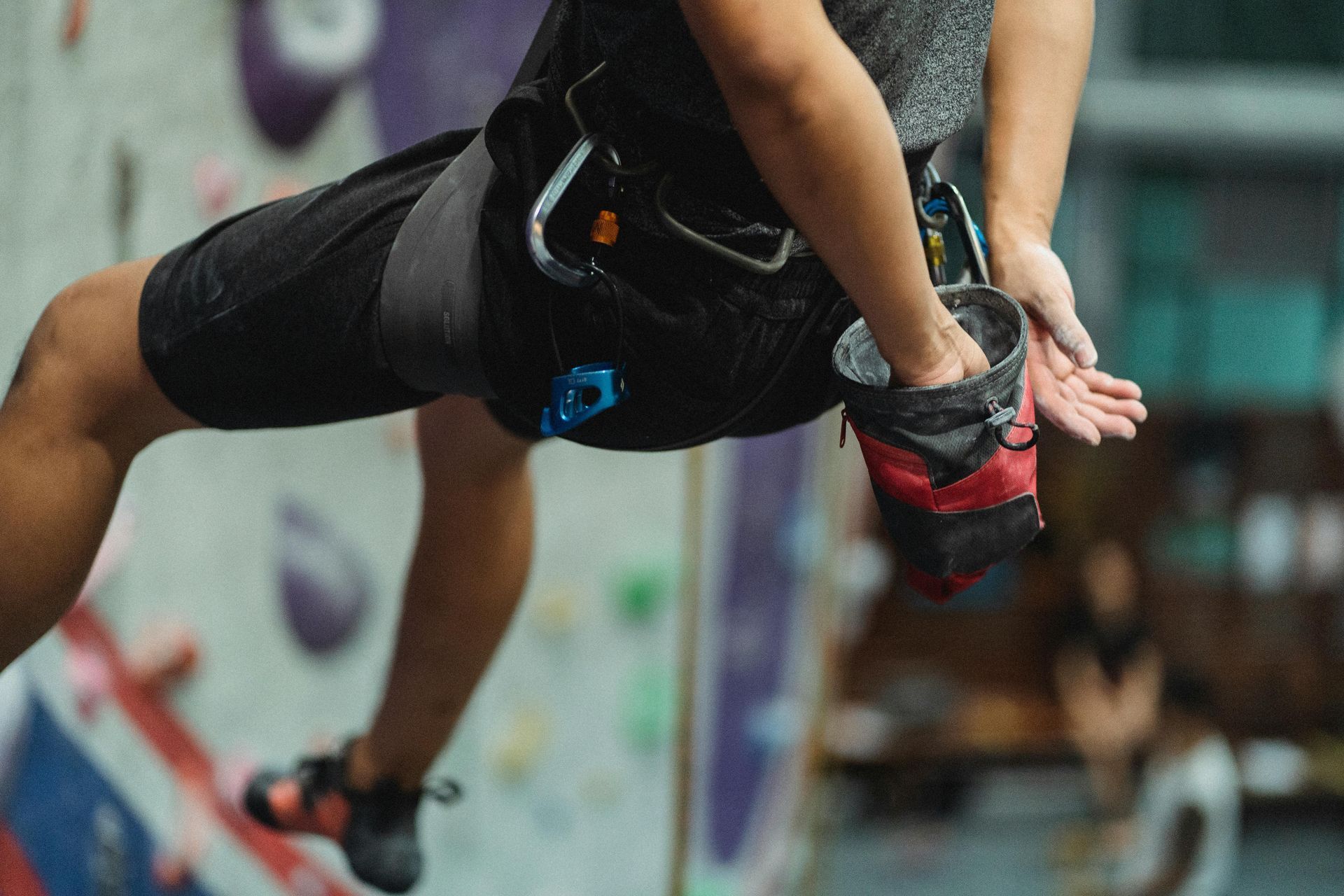 A person is climbing a climbing wall in a gym.