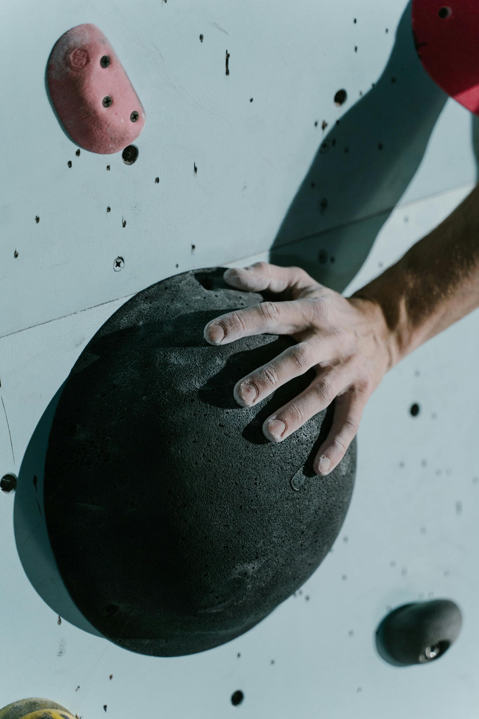 A person 's hand is reaching for a rock on a climbing wall.
