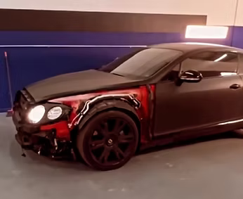 A black car with a red fender is parked in a garage | AP Autohouse