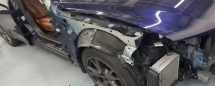A purple car with the fender removed is sitting in a garage | AP Autohouse