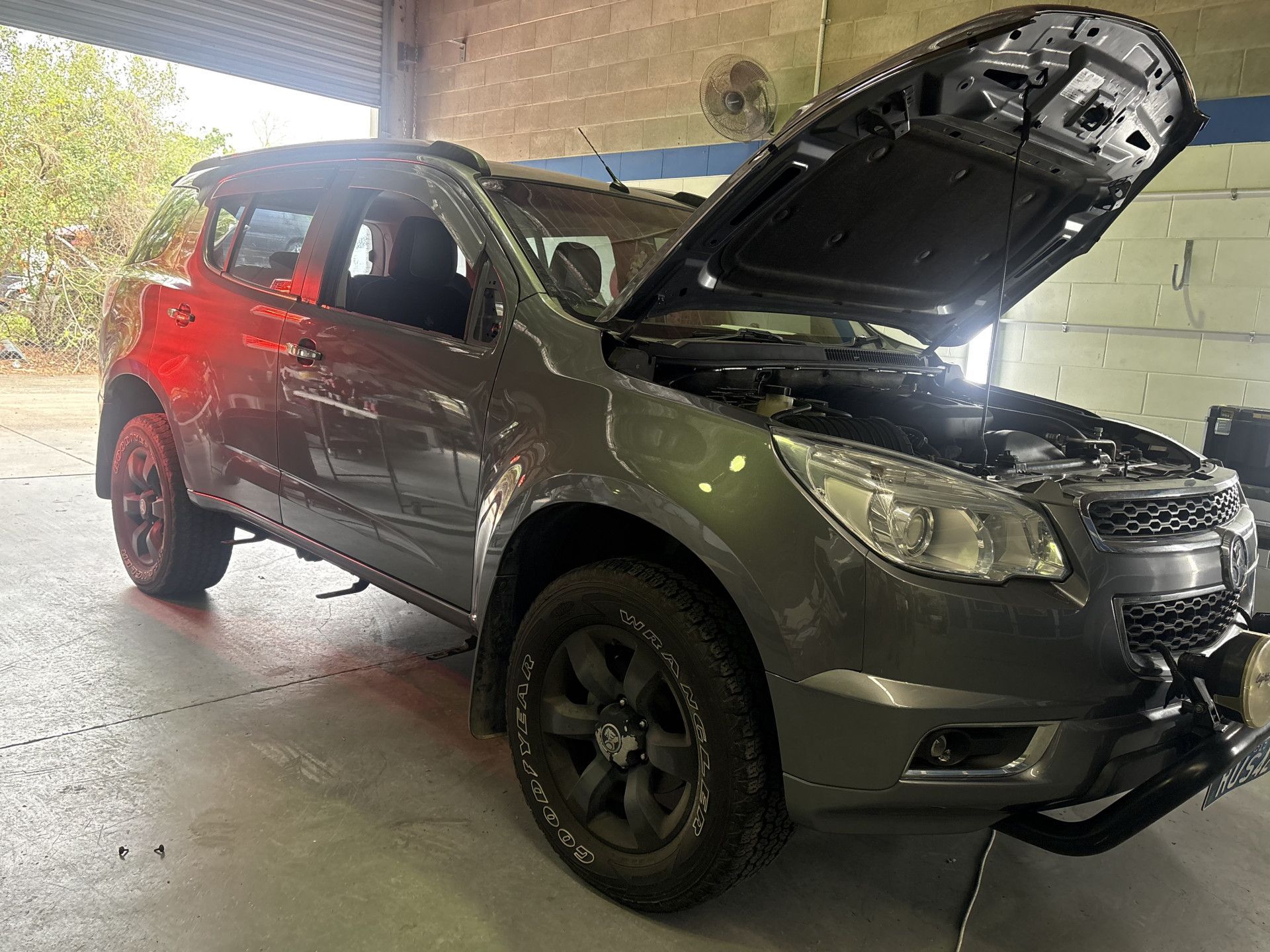 Gray SUV with hood open in a garage, possibly for repair.— Airlie Beach Smash Repairs in Cannonvale, QLD