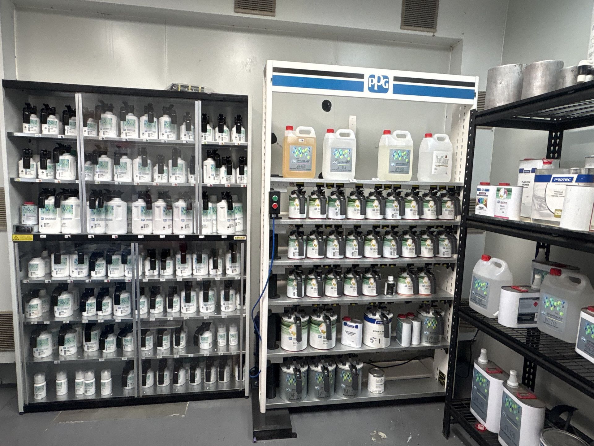 Shelves filled with various paint cans and containers in a workshop setting.— Airlie Beach Smash Repairs in Cannonvale, QLD
