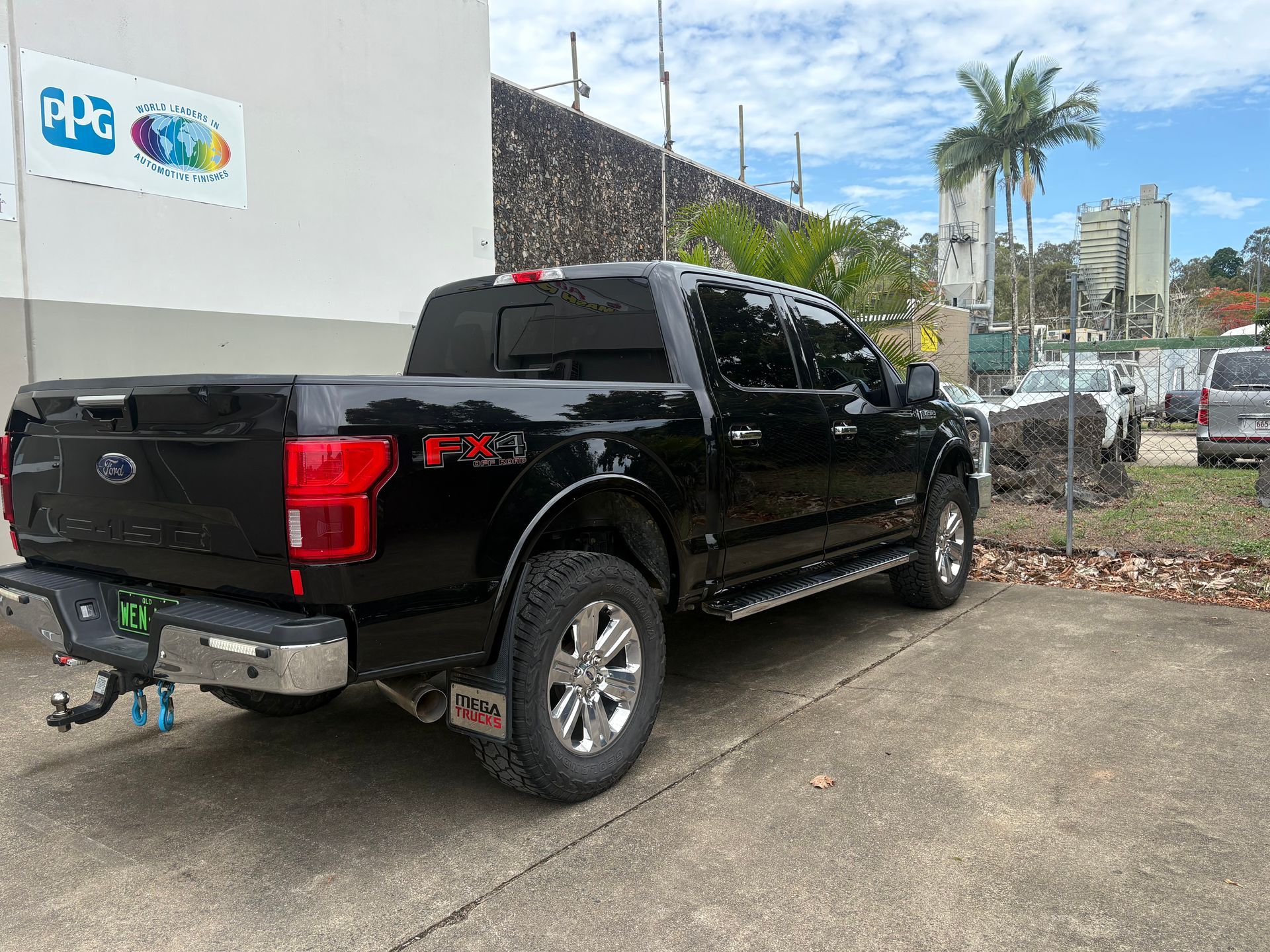 Black Ford F-150 pickup truck parked near a building with PPG logo.— Airlie Beach Smash Repairs in Cannonvale, QLD