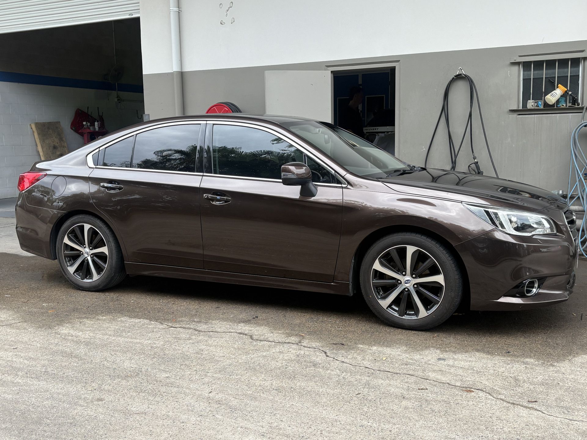 Brown Subaru Legacy sedan parked outside a garage.— Airlie Beach Smash Repairs in Cannonvale, QLD