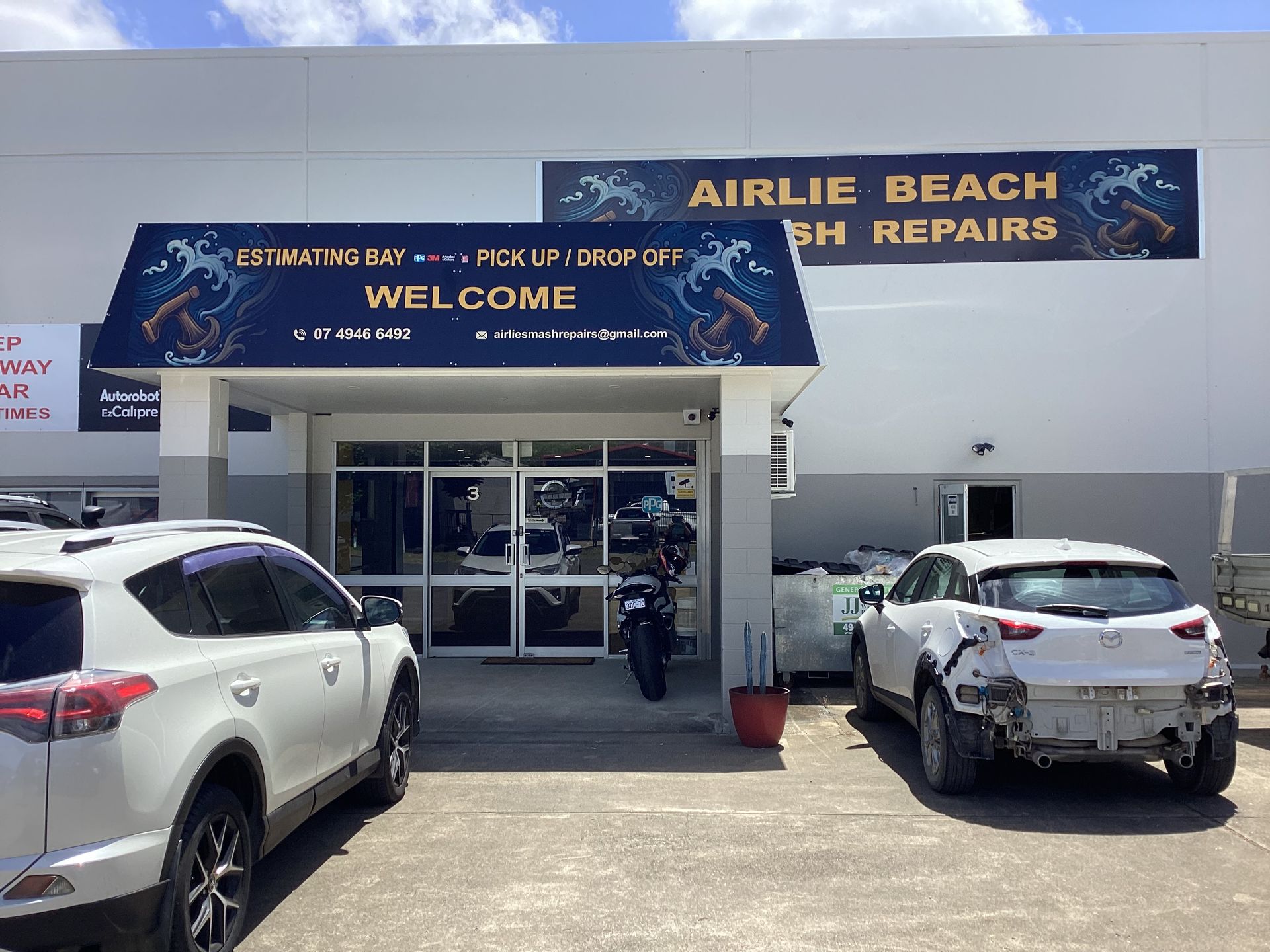 Person Applying Clear Protective Film to a Black Car's Fender, Indoors — Airlie Beach Smash Repairs in Cannonvale, QLD