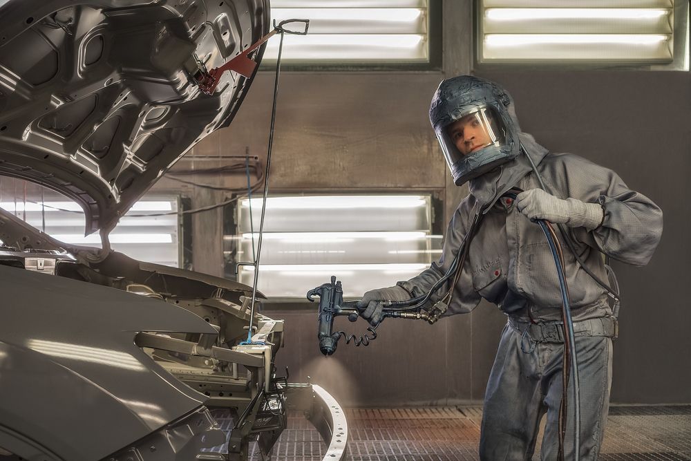 Person in Protective Suit Painting a Car in a Spray Booth — Airlie Beach Smash Repairs in Cannonvale, QLD