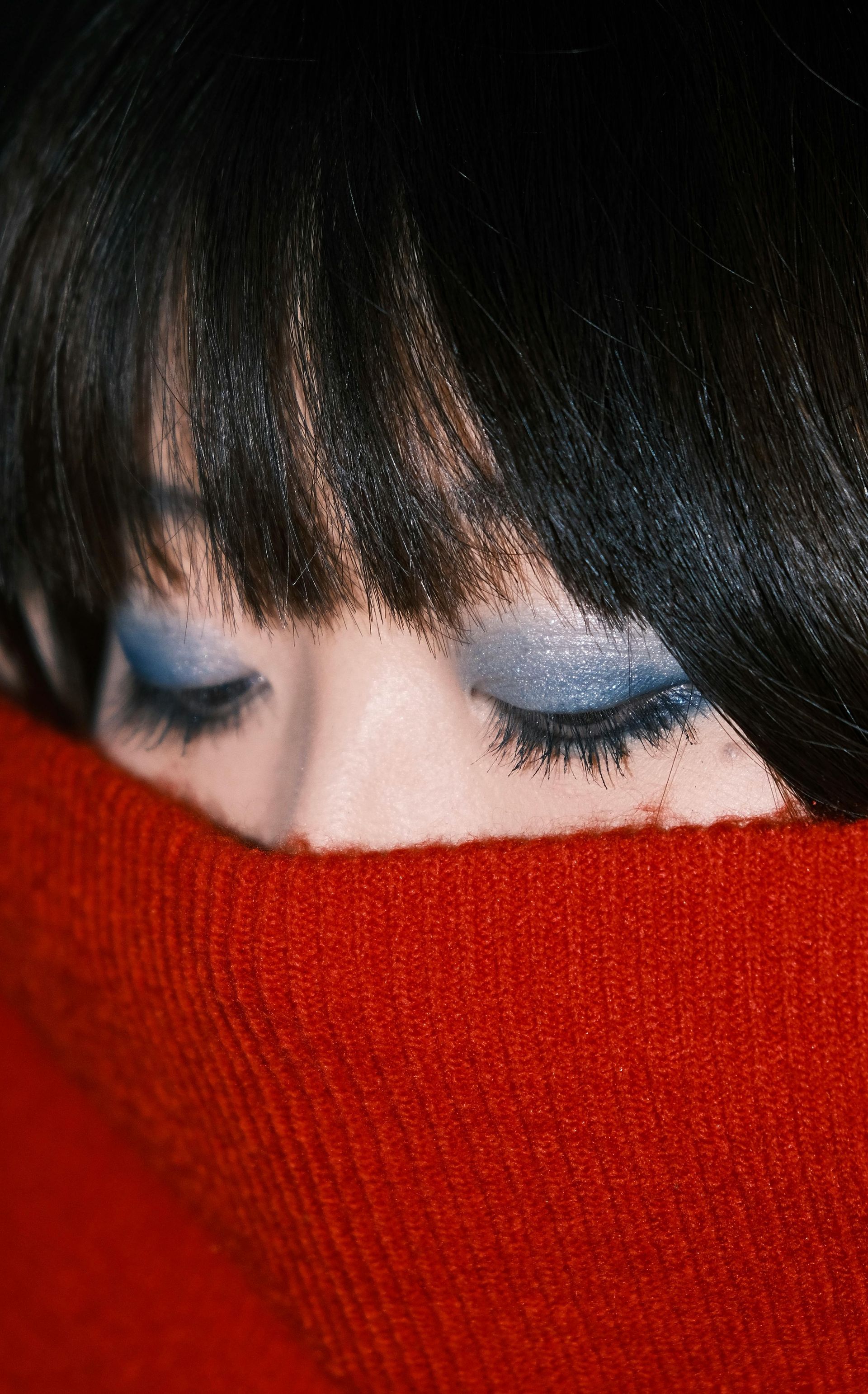 Woman's face half hidden by turtle neck sweater.