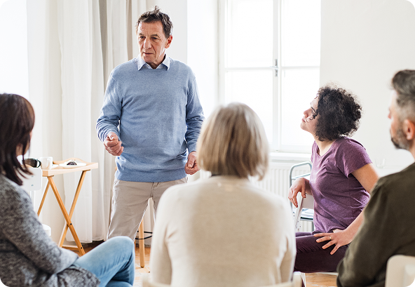 Young woman with dark hair smiling, talking on a cell phone at a desk. A plant and pens are in the background.