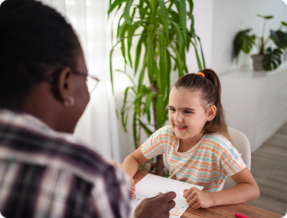 A woman gestures while speaking to a boy; both are seated on a couch, with the boy appearing sad.