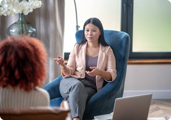 Group therapy session: Five people seated in a circle, smiling and talking in a brightly lit room.